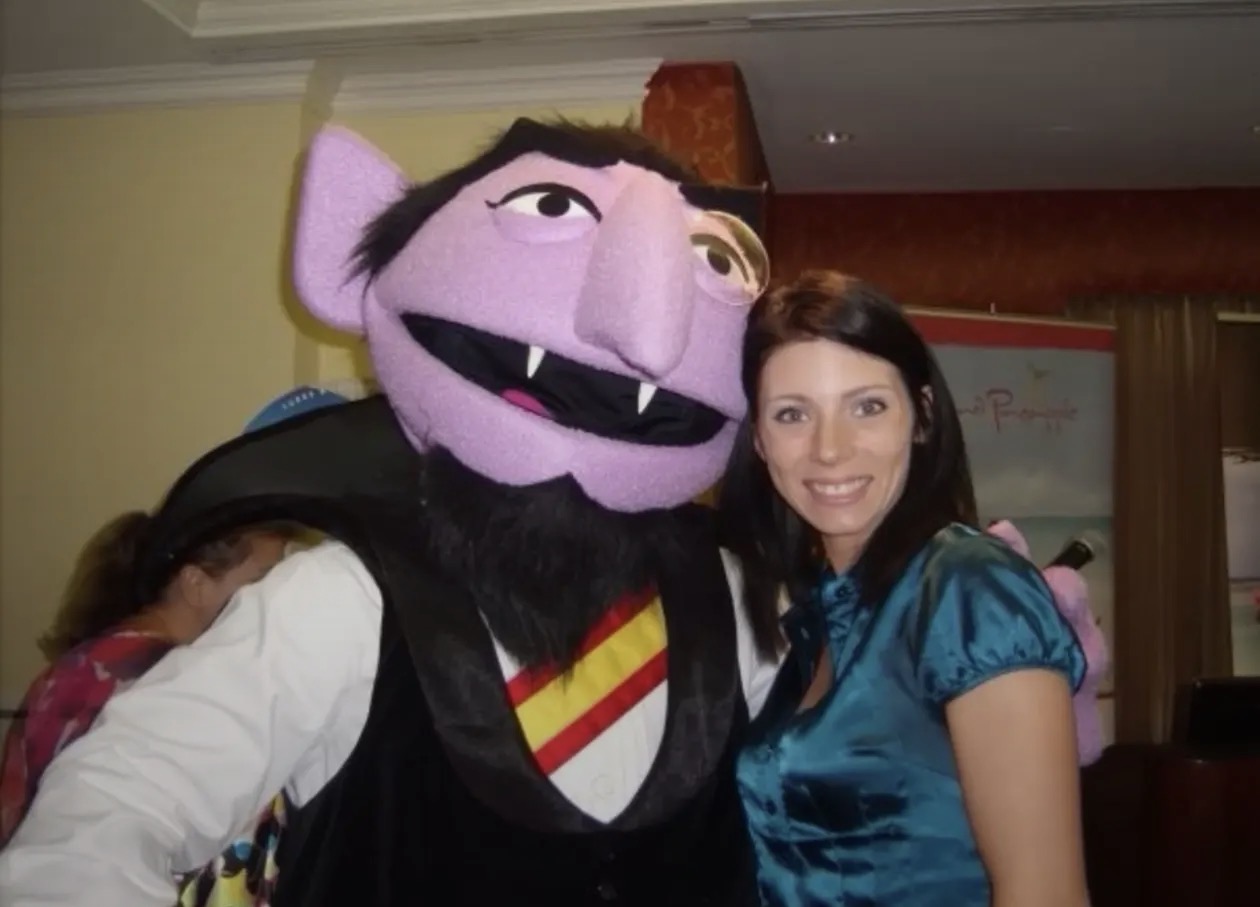 Rae-Ann smiling beside a Count Dracula character at a conference in Turks and Caicos